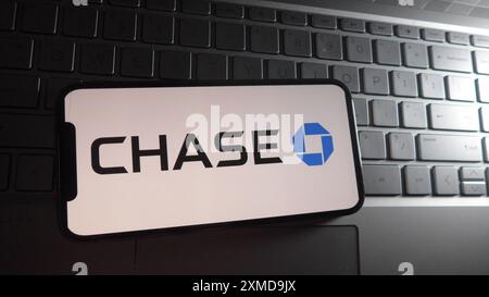 In this photo illustration, CHASE logo is displayed on a smartphone with a laptop keyboard background. Stock Photo