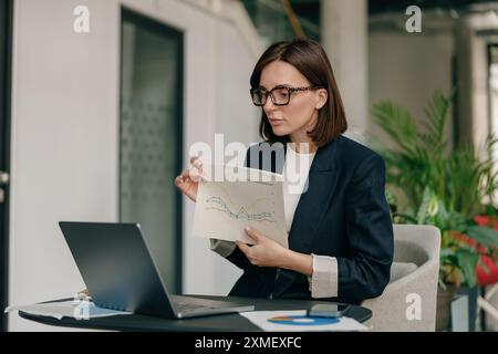 A businesswoman is focused on analyzing financial reports in a modern office setting Stock Photo
