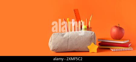 Pencil case, apple and different school stationery on orange background with space for text Stock Photo