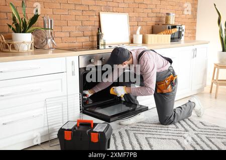 Male technician repairing electric oven in kitchen Stock Photo