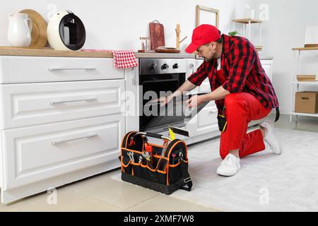 Male technician checking oven in kitchen Stock Photo