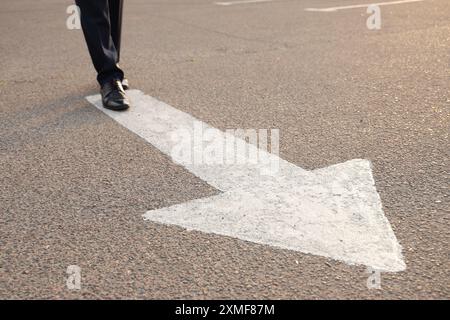 Businessman walking along road with arrow marking. Concept of career choice Stock Photo