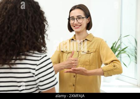 Young women using sign language for communication indoors Stock Photo