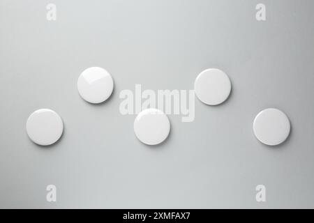 Blank white button badges on grey background, top view. Mockup for design Stock Photo