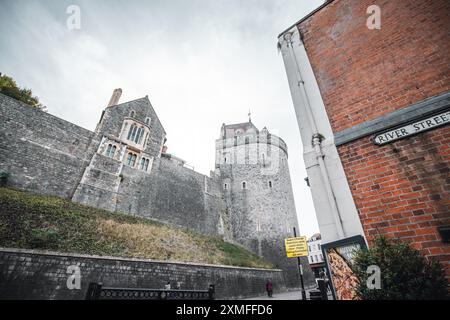 Windor Castle, UK - October 16, 2023 : A stone castle wall with a round tower and a red brick building, a street sign for "River Street" on the red br Stock Photo