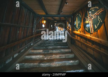 Austria - October 26, 2023 : A stone staircase winds upwards inside a dimly lit wooden building. The walls are lined with wooden planks and decorated Stock Photo