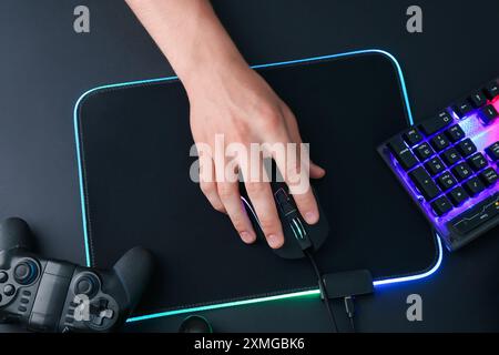 Gamer using modern wired computer mouse at black table, top view Stock Photo