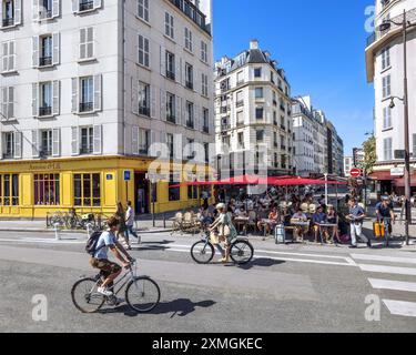 FRANCE. PARIS (75) 10TH DISTRICT. CYCLISTS PASS BY THE RESTAURANT TERRACE NEAR THE COLORFUL SHOPS OF QUAI DE VALMY Stock Photo