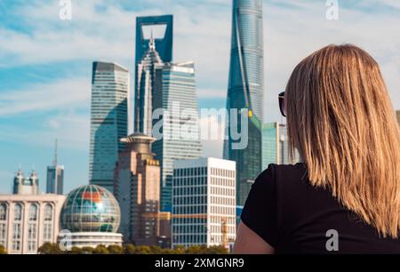 Young woman stands captivated by the impressive skyline of Shanghai. Stock Photo