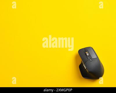 Black wireless computer mouse on yellow background. Top view with copy space. Stock Photo
