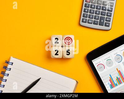 Year 2025 business goals concept. Year 2025 with target symbol on wooden cubes over yellow office desktop background. Stock Photo