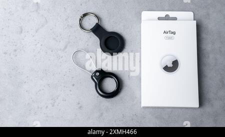 Jurmala, Latvia 25.06.2024: On the grey background is a white Apple airtag box and two different tag mount keychains. Stock Photo