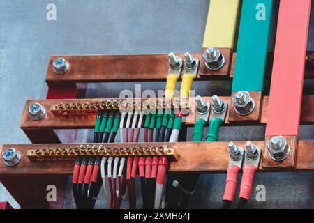 Many power electric wires multi-colored wires and nuts connected to copper metal busbars electric three phases of high industrial voltage. Electricity Stock Photo