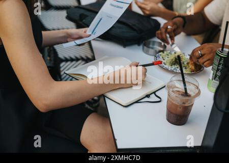 Business meeting with colleagues discussing documents and notes over lunch at an outdoor table Stock Photo