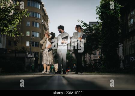 Three business professionals walking through urban city street having a casual conversation Stock Photo