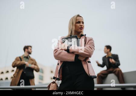 Confident businesswoman with tablet outdoors on a rooftop with male colleagues Stock Photo