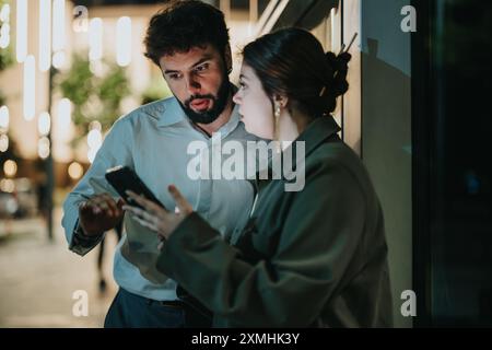 Two colleagues discussing important project details outside at night Stock Photo