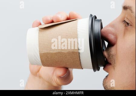 Close up of guy drinking from paper cup isolated on white studio background Stock Photo