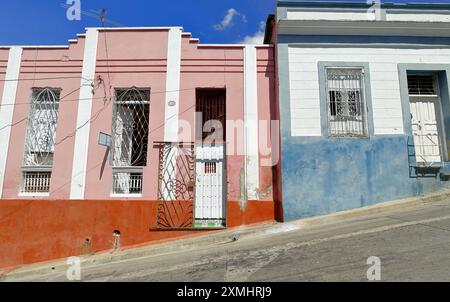 Santiago, Cuba-October 20, 2019: Pink with white molding and red dado wall, white with blue molding and dado facade, one-storey Colonial townhouses on Stock Photo