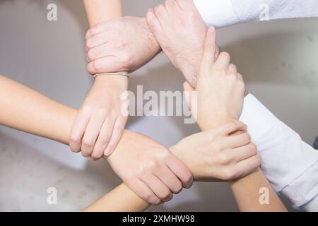 High angle shot of a group of businesspeople holding one another's wrists in a circular formation Stock Photo