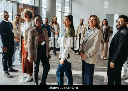 Group of people attending a business seminar in the workplace, looking happy and engaged with the presentation. Stock Photo