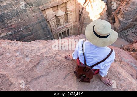 Woman traveler sitting on carpet viewpoint in Petra ancient city looking at the Treasury or Al-khazneh, famous travel destination of Jordan and one of Stock Photo