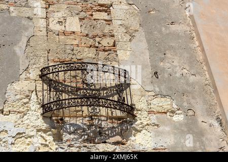 Rustic balcony with ornate railing mounted on a weathered stone wall. Stock Photo