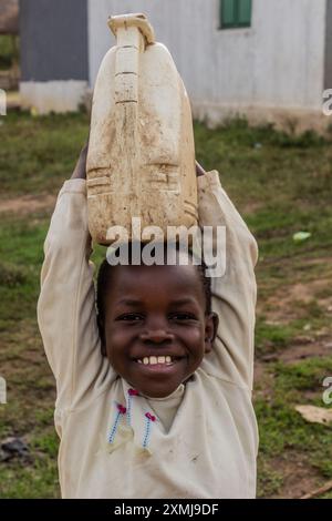 KATUNGURU, UGANDA - MARCH 16, 2020: Happy boy with plastic jerrycan in Katunguru village, Uganda Stock Photo