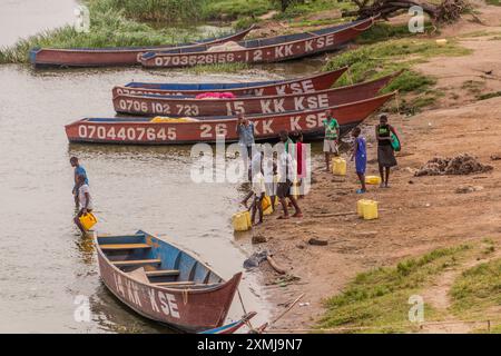 KATUNGURU, UGANDA - MARCH 16, 2020: Children collect water from Kazinga Channel in Katunguru village, Uganda Stock Photo