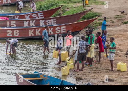 KATUNGURU, UGANDA - MARCH 16, 2020: Children collect water from Kazinga Channel in Katunguru village, Uganda Stock Photo