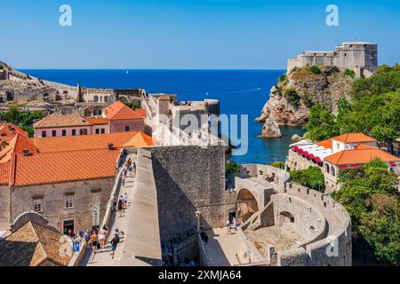 DUBROVNIK, CROATIA - JUNE 29, 2024: Tourists walk around spectacular ancient city walls which encircle Dubrovnik's historic Old City, Stock Photo