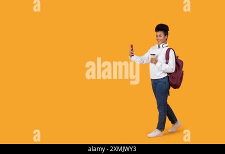 Young Woman Taking Selfie While Walking With Backpack and Coffee Stock Photo