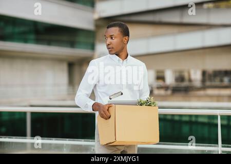 African American Man Carrying Box Leaving Workplace Stock Photo
