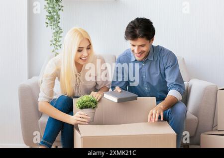 Young man and woman packing things in moving boxes indoor Stock Photo
