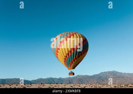 Hot air balloon flying over Palm Springs desert at sunrise. Stock Photo