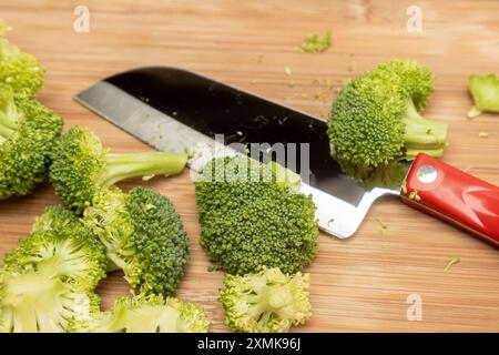 Broccoli heads chopped on a cutting board with a Santoku Knife in the background Stock Photo