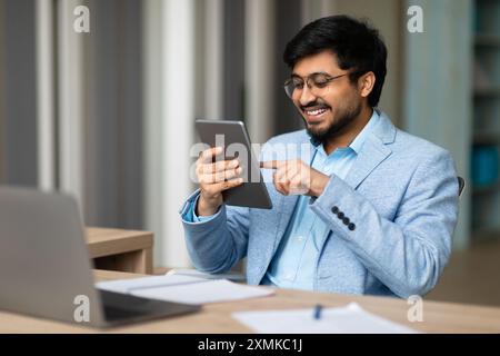 Smiling Indian Man Using Tablet In Office Stock Photo