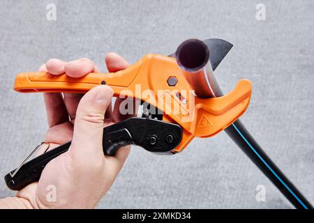 Pvc Cut Off Orange ratcheting PVC pipe cutter tool in hand of plumber cutting off ...