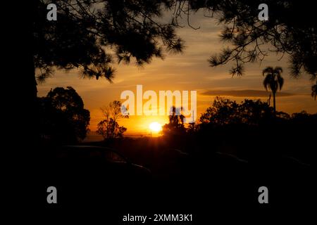 sunset on a farm with silhouettes of cars and trees Stock Photo