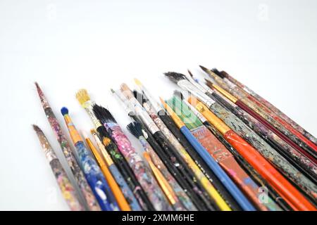 Dirty paint brushes well used and covered in paint on white background – Wales, UK  – 19 July 2024 Stock Photo