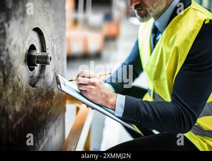 Portrait of engineer controlling machine in modern industrial factory. Manufacturing facility with robotics, robotic arms and automation. Storing Stock Photo