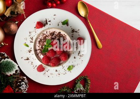 Delicious raspberry mousse with red berries from an overhead perspective. Table with Christmas decoration. Stock Photo