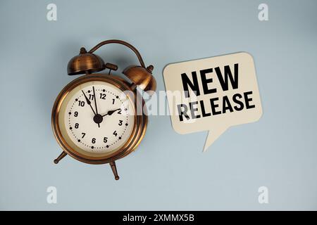 New Release text on speech bluble with alarm clock top view on blue background Stock Photo