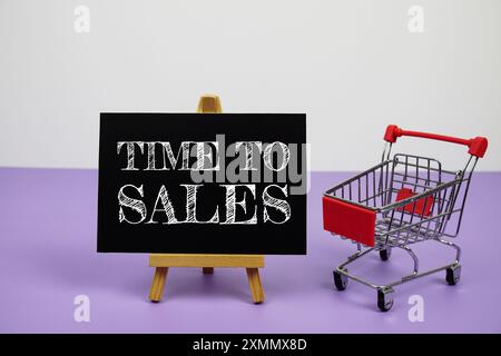 Time to Sales text message and trolley shopping cart on purple background Stock Photo