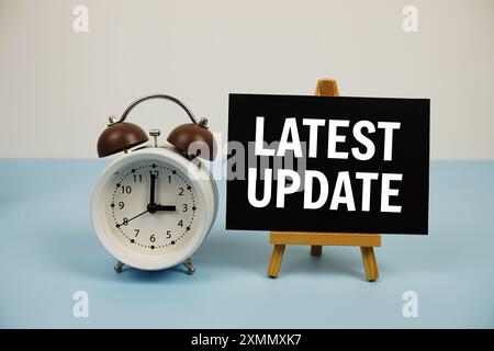 Latest Update text on paper card with alarm clock on blue background Stock Photo