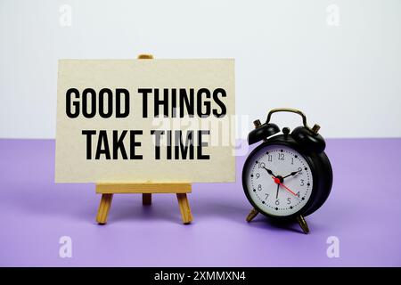 Good things take time text on paper card with alarm clock on purple background Stock Photo