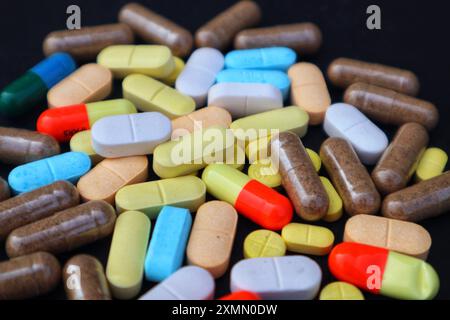 Various kinds of medicine tablets, capsules and caplets mixed in close view on black background. Stock Photo