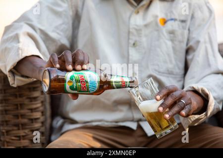 Zambian pouring local Mosi beer into a beer glass Stock Photo