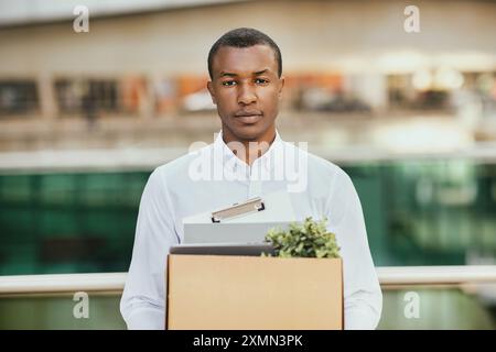 Young Man Carrying Cardboard Box Outside Office Building Stock Photo