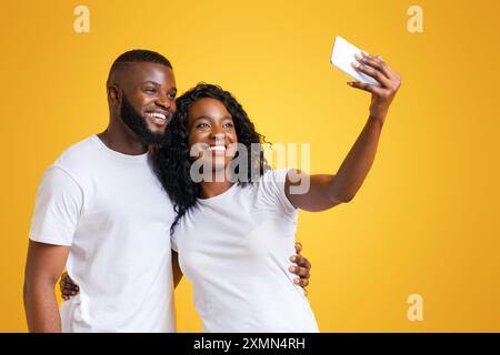Couple Taking Selfie on Yellow Background Stock Photo
